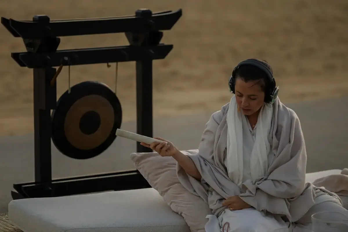 A facilitator with a gong and copal at a beach ceremony
