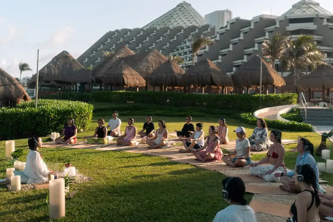 A large group gathered for a collective session on a resort lawn at dusk