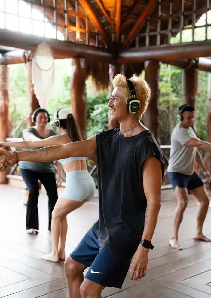 A movement session under a palapa, participants wearing wireless headphones