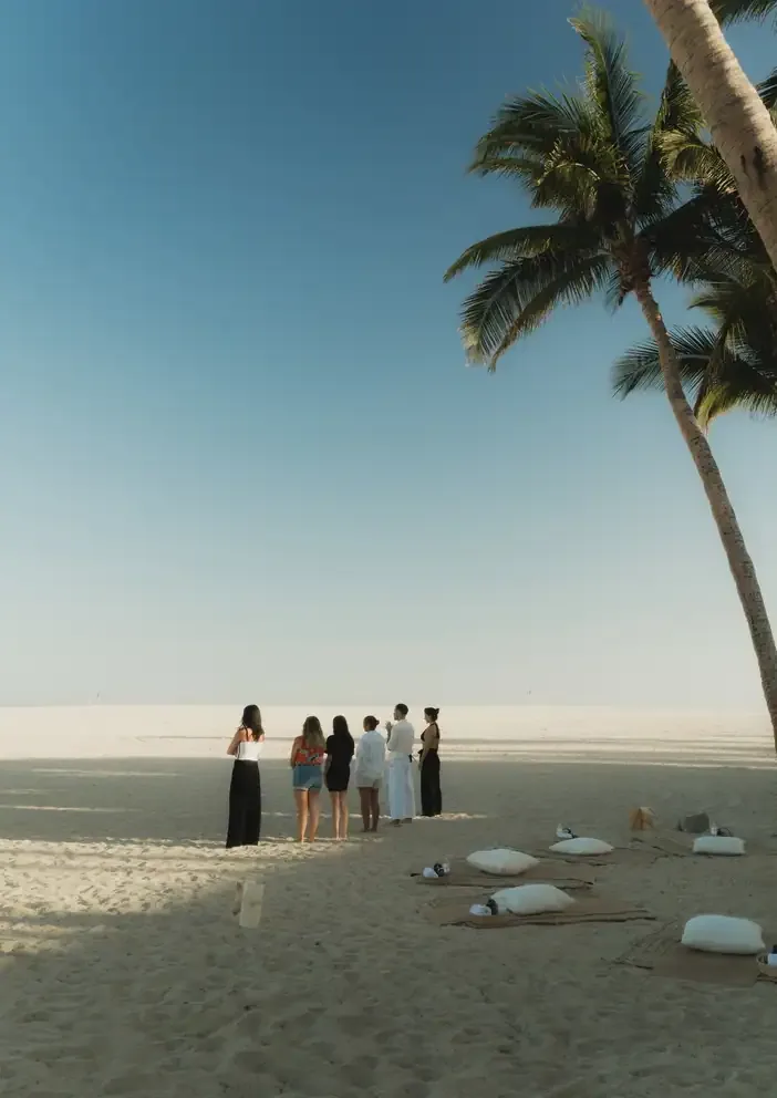 A hotel team gathered on the beach at sunset before a session