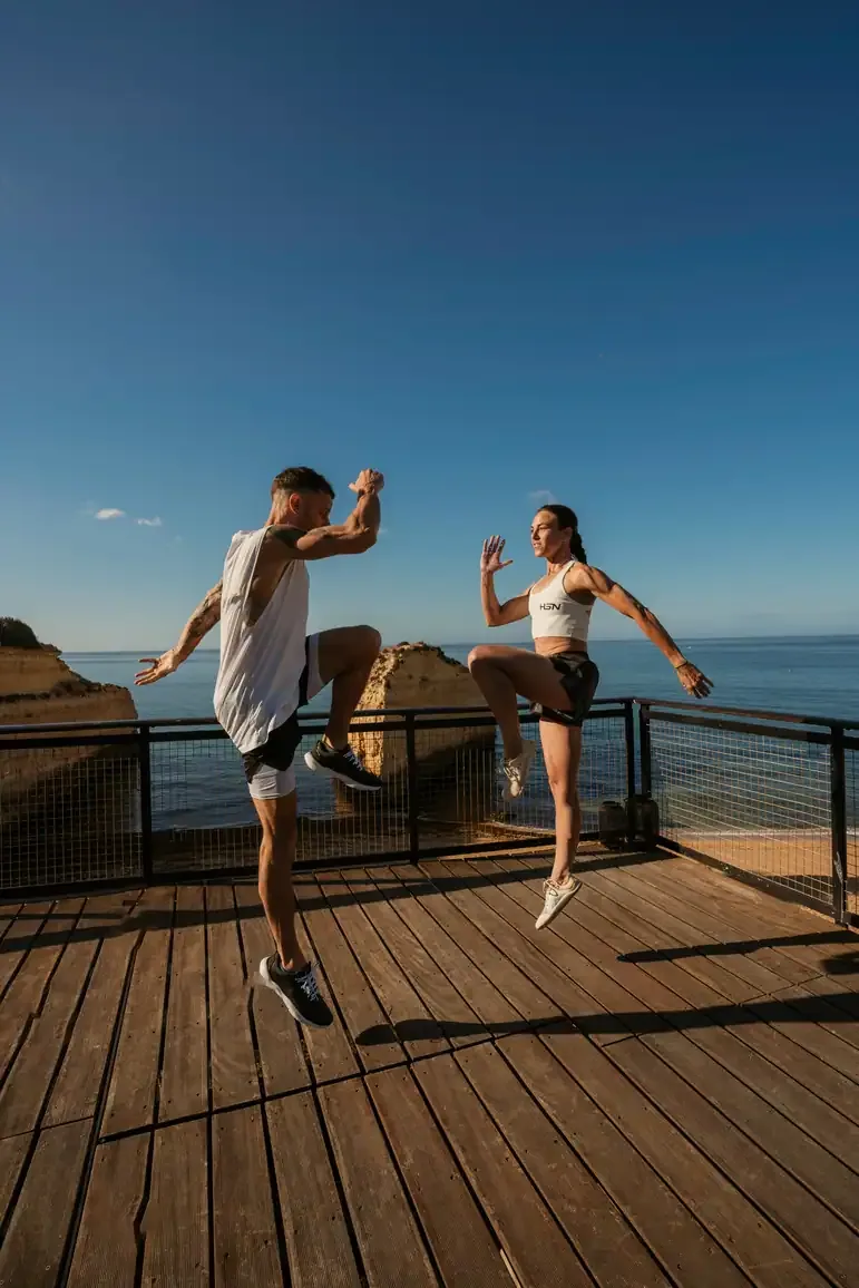 Two guests mid-movement on a wooden deck above the sea