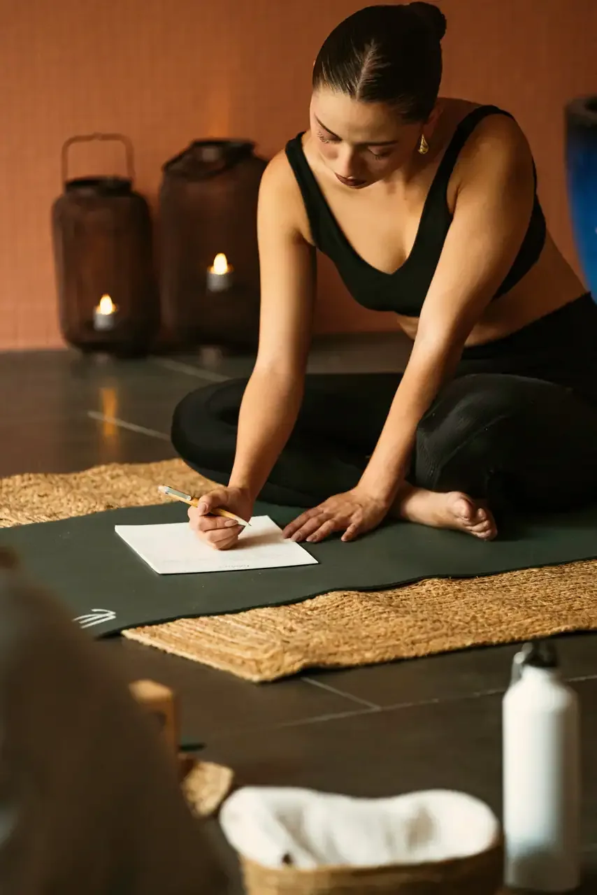 A practitioner writing beside candles on a mat in a warm interior